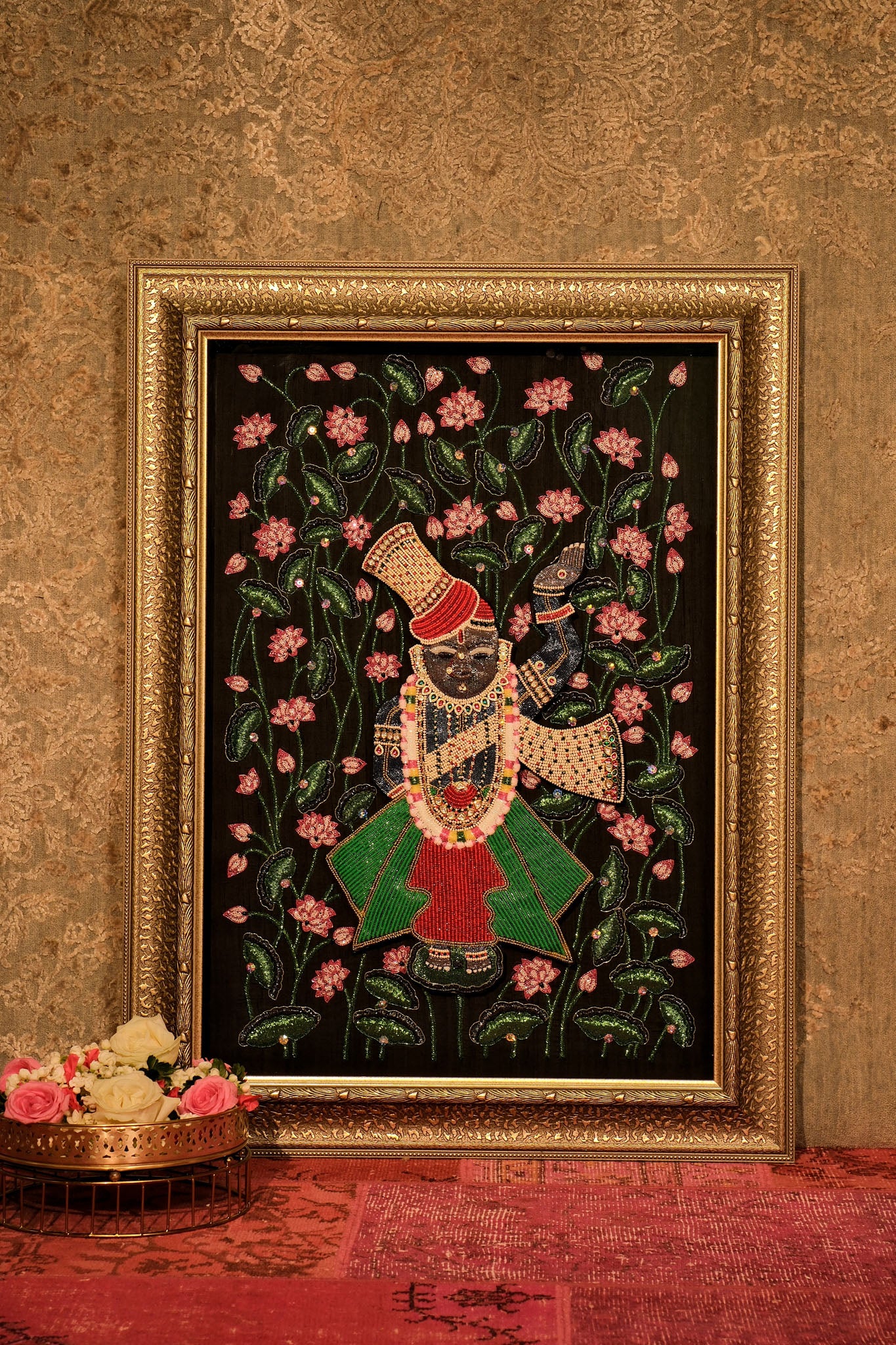 Decorative painting of a figure with flowers in a gold frame on a textured wall.